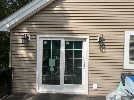 A new sliding glass door installed on a sided home